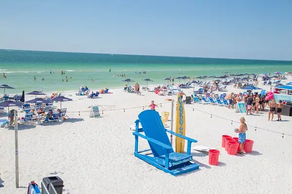 Treasure Island beach scene with blue chair and umbrellas, illustrating coastal cleaning challenges.